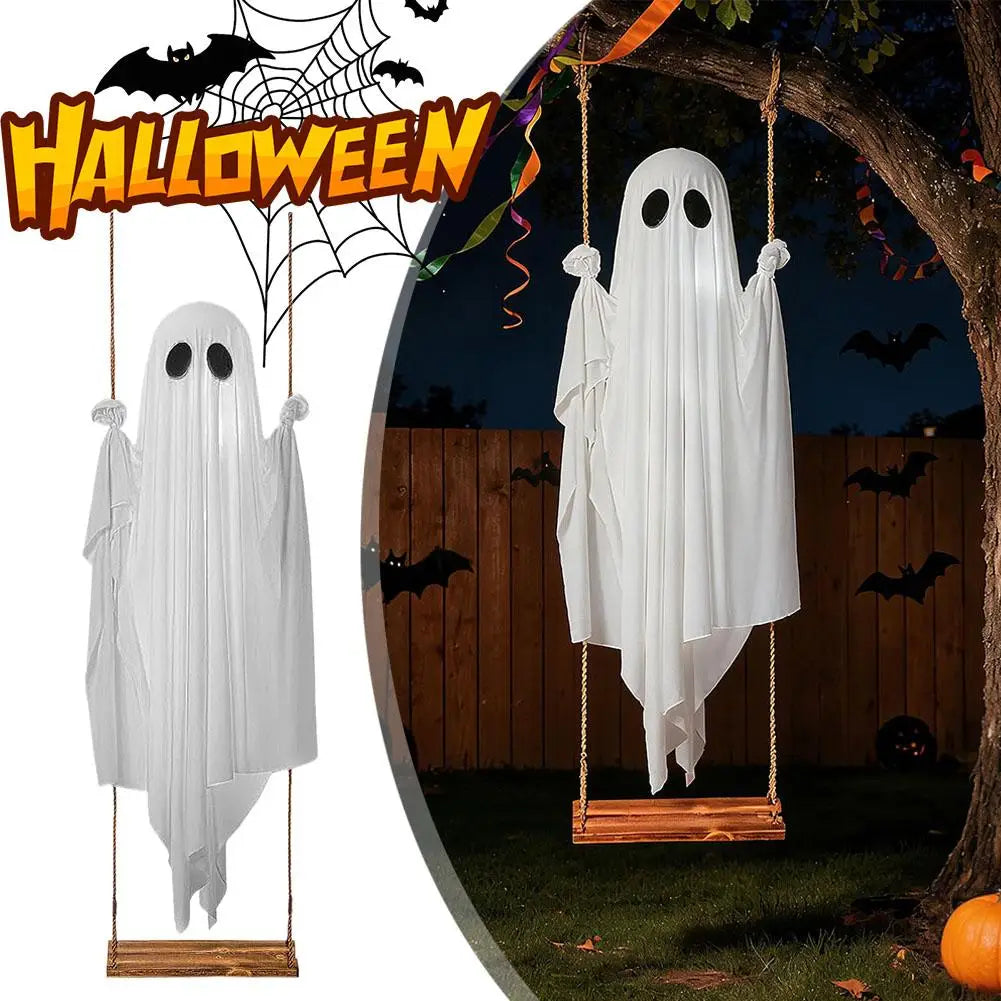 A white ghost decoration hangs from a tree branch in an outdoor Halloween setting.