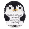 A black and white crocheted penguin plush with an encouraging message card attached.