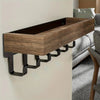 A rustic wooden floating shelf with hooks mounted on a white wall.