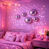 A bedroom decorated with pink lighting and a headboard featuring a set of silver disco ball wall decor