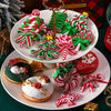 A plate displays a set of sixteen wooden candy cane Christmas ornaments in red and green, including wreaths and bows.