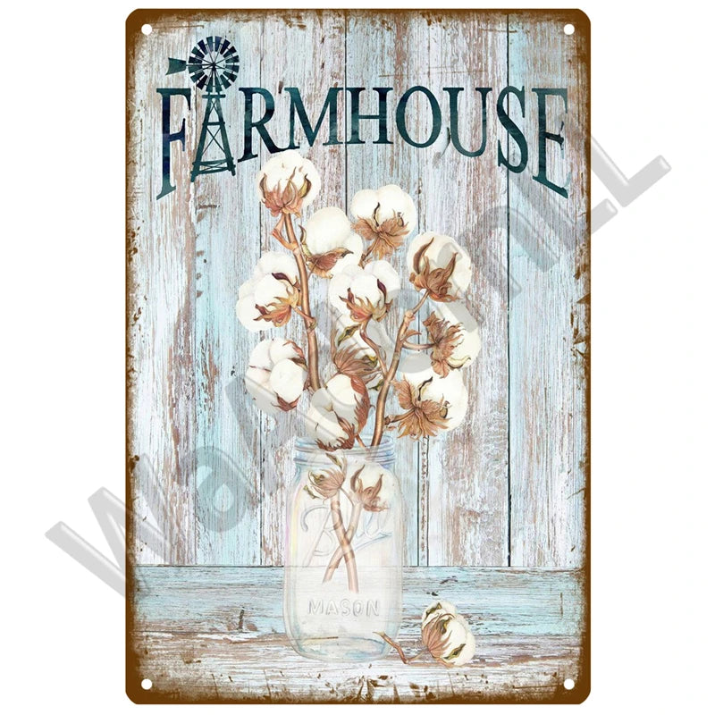 A rustic metal sign featuring the word FARMHOUSE and a bouquet of dried white flowers in a glass jar.