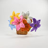 A hand-crocheted bouquet of colorful artificial lily flowers in shades of yellow, pink, orange, white, and purple, resting in