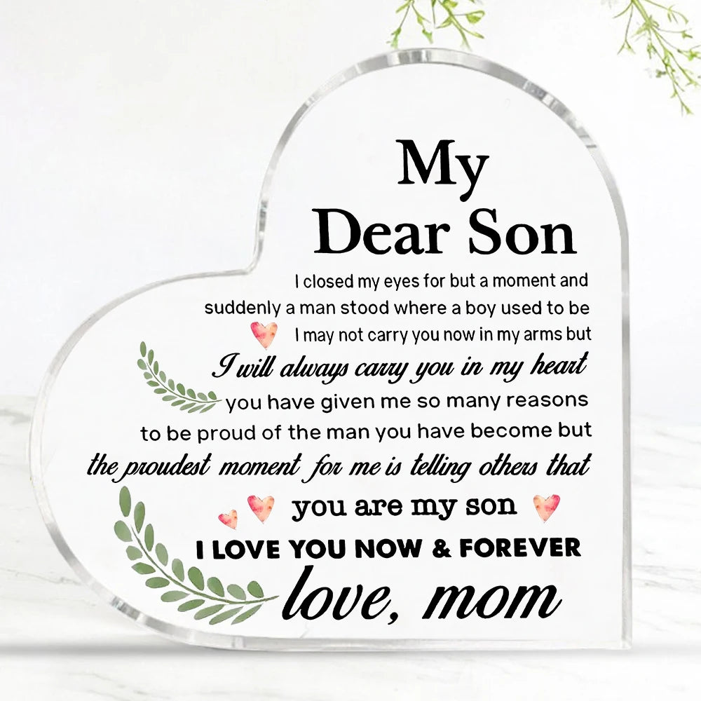 A clear heart-shaped acrylic keepsake plaque with engraved text saying My Dear Son and I love you now & forever, mom.