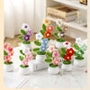A collection of hand woven crochet flowers in various colors potted in white ceramic containers on a marble surface.