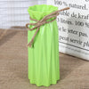 A lime green plastic vase with a woven natural fiber rope tied around the neck, sitting on burlap fabric.