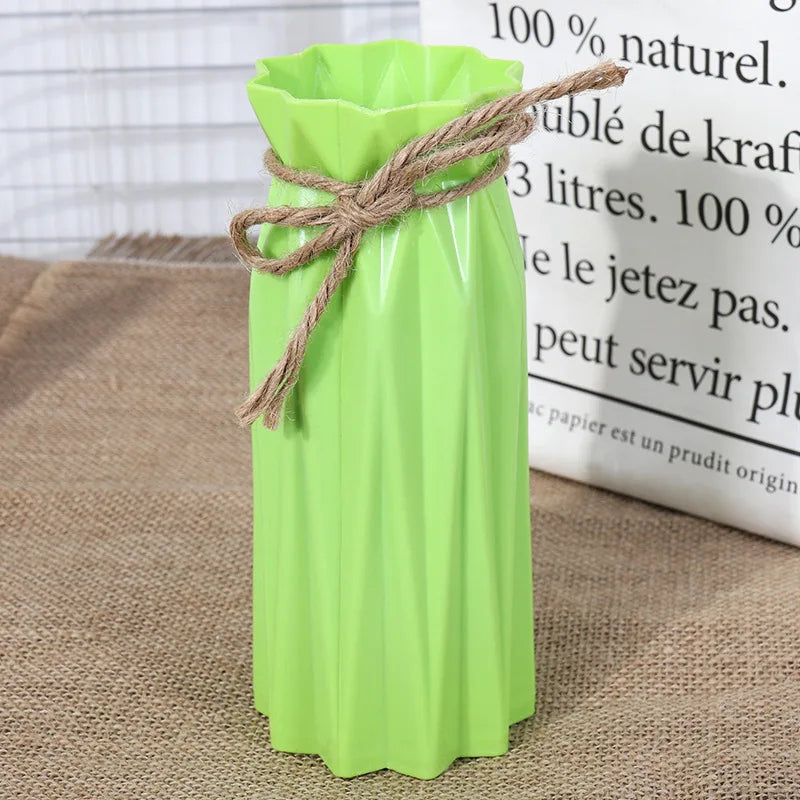 A lime green plastic vase with a woven natural fiber rope tied around the neck, sitting on burlap fabric.