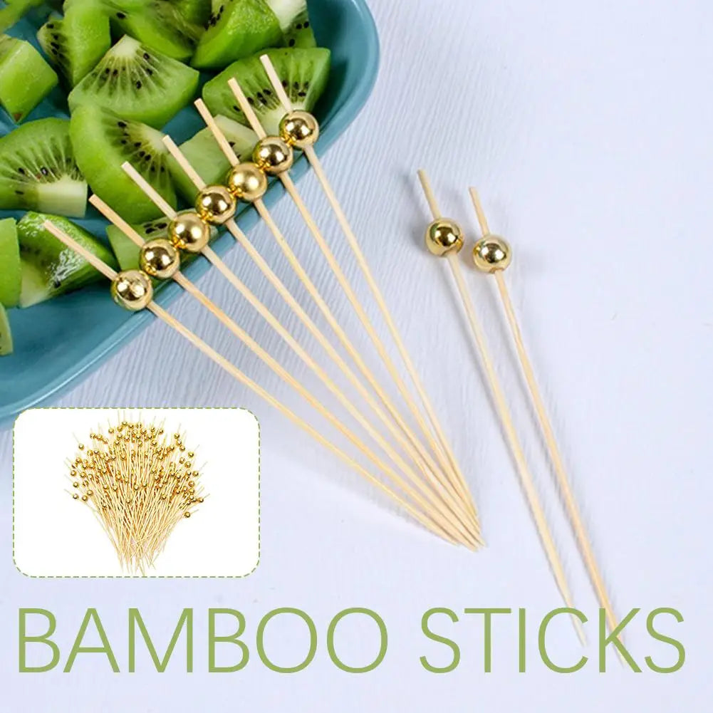 Gold accent bamboo sticks with spherical balls used as cocktail skewers for fruit and appetizers