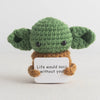 Handmade crochet potato doll with green skin and brown features, featuring an inspirational slogan tag.