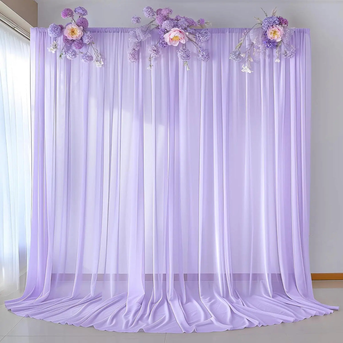 Purple chiffon backdrop curtain with floral accents used for wedding and event decor