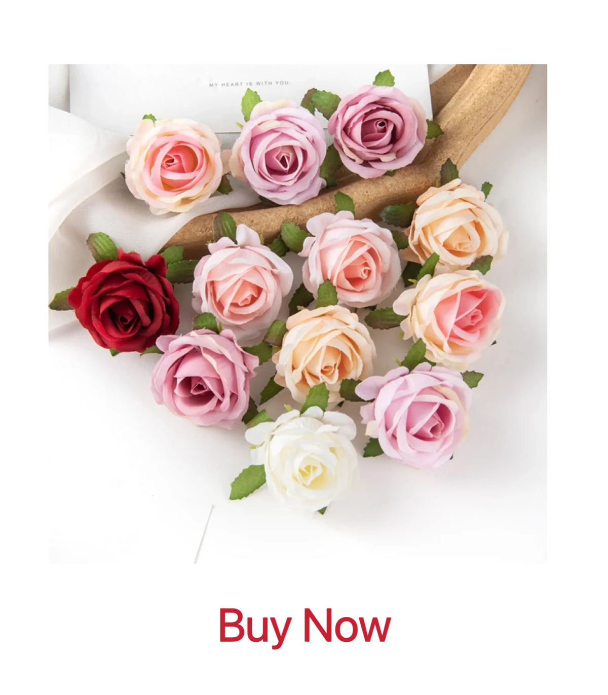 A bouquet of artificial roses and peonies in shades of pink, peach, and red arranged on a wooden surface.