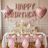 Pink marble birthday balloon decoration set featuring a banner and pink balloons on a table.