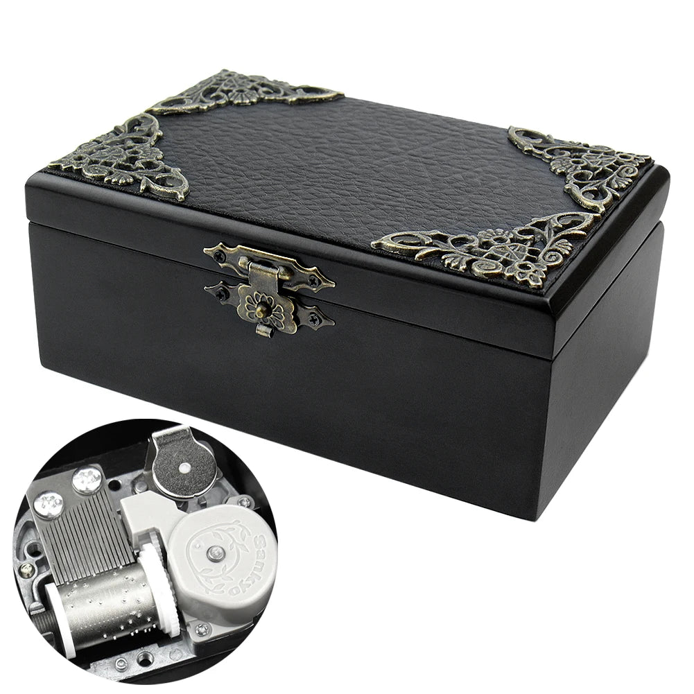 A black hand-cranked wooden music box with ornate gold detailing and an open mechanism shown separately.