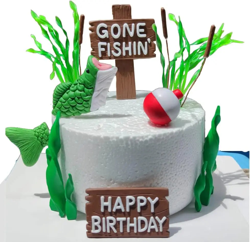 A white cake decorated with fishing theme elements including a fish, a wooden cross sign saying Gone Fishin', and a birthday 