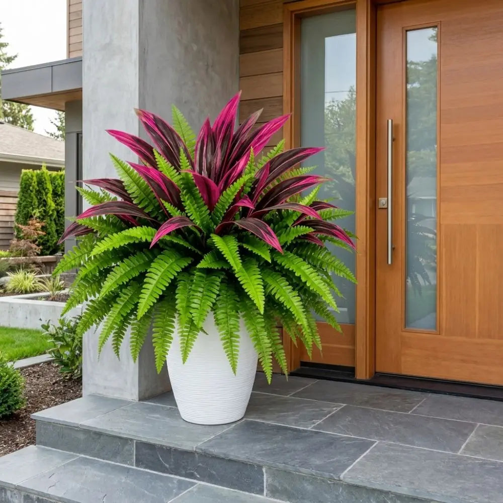 A potted artificial Dracaena Boston fern with vibrant magenta and green leaves sits on a stone step outside a modern wooden d