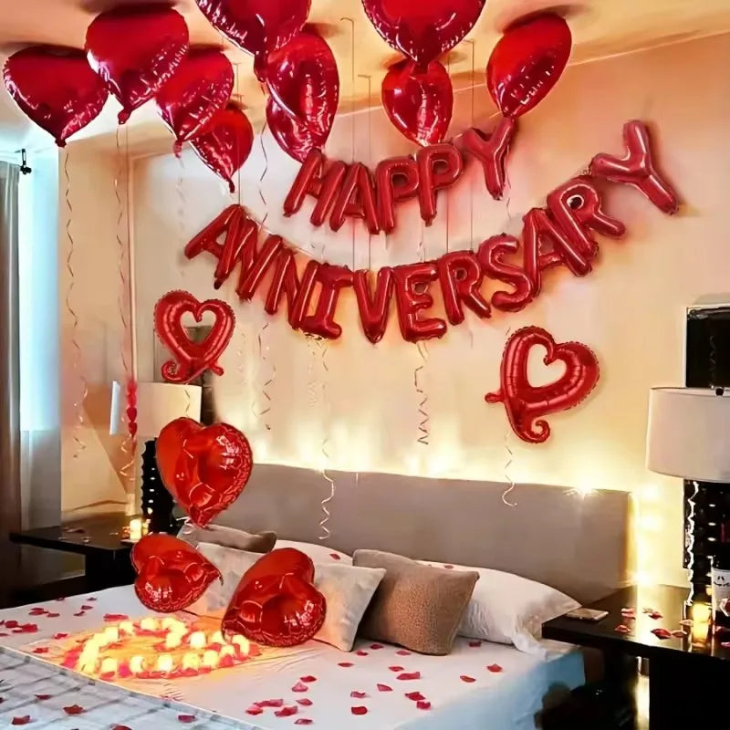 Red heart foil balloons spelling out Happy Anniversary decoration above a bed
