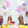A group of children celebrating a birthday with balloons and crafts on a table.