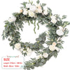 A wreath of green eucalyptus leaves and white and peach roses used for weddings and events