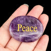 A hand holds a smooth, oval purple amethyst crystal for Feng Shui and healing.