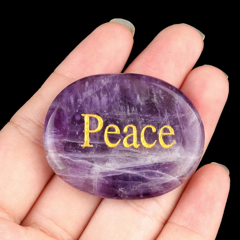 A hand holds a smooth, oval purple amethyst crystal for Feng Shui and healing.