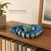 A blue and gray flexible articulated snake desk toy with a head resting on a wooden surface.
