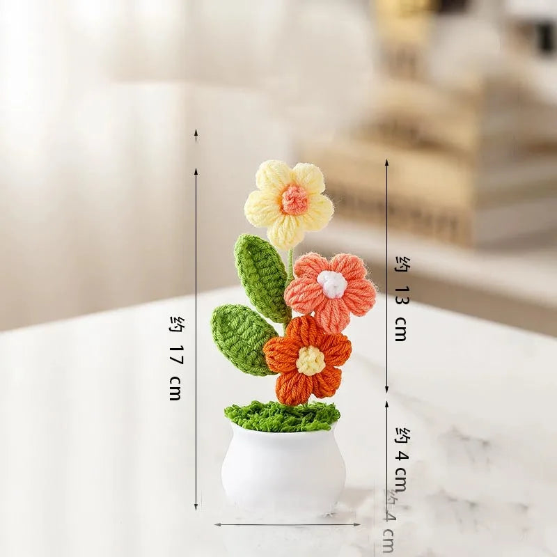 Hand woven crochet flowers in yellow and orange colors displayed in a white pot