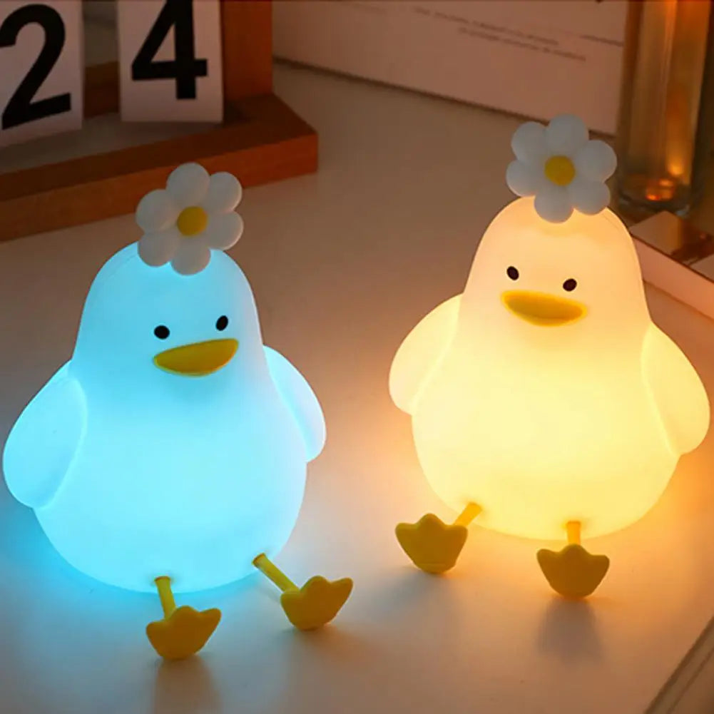 A glowing white duck night light with yellow feet and a flower on its head.
