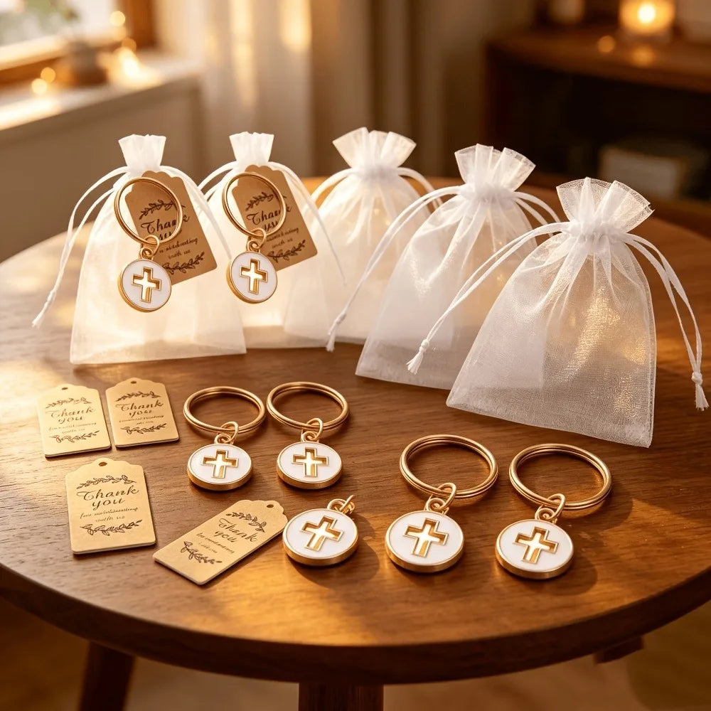Several white organza bags with gold cross keychains and thank you cards are displayed on a wooden table.