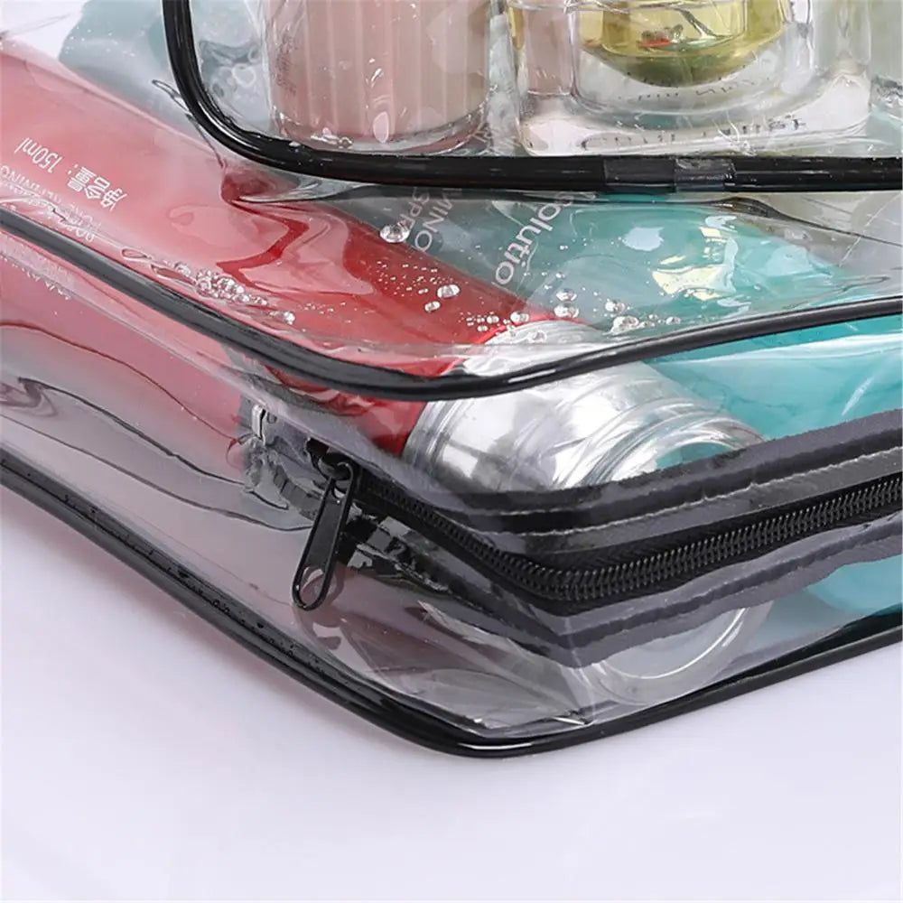 A transparent waterproof toiletry bag with a black zipper, containing various cosmetic products.