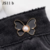 A black denim garment featuring a gold-edged, black butterfly button with a pearl center.