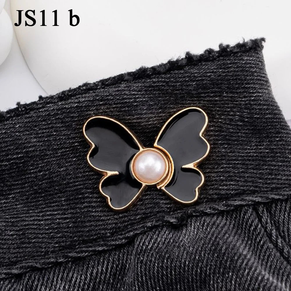 A black denim garment featuring a gold-edged, black butterfly button with a pearl center.