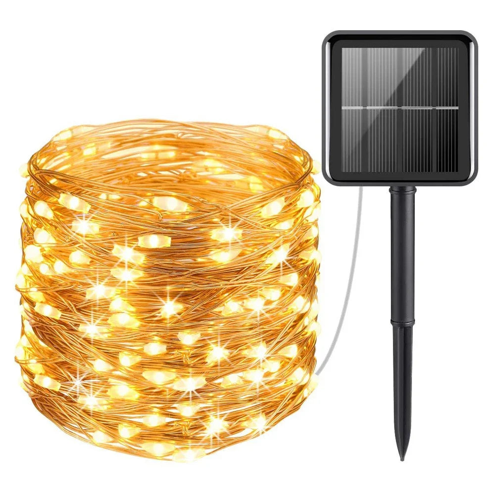 A spool of warm yellow fairy string lights with a black solar panel attached for outdoor decoration.