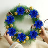 Hands hold a wreath of blue glitter artificial poinsettia flowers and pinecones for Christmas décor