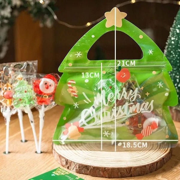 A green reusable Christmas gift bag with a star handle and festive decorations sits on a wooden surface.