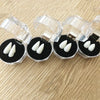 Realistic vampire fangs with adjustable fit displayed on clear plastic holders.