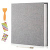 A grey linen scrapbook photo album with a wooden tool and colorful adhesive stickers displayed on a white surface.