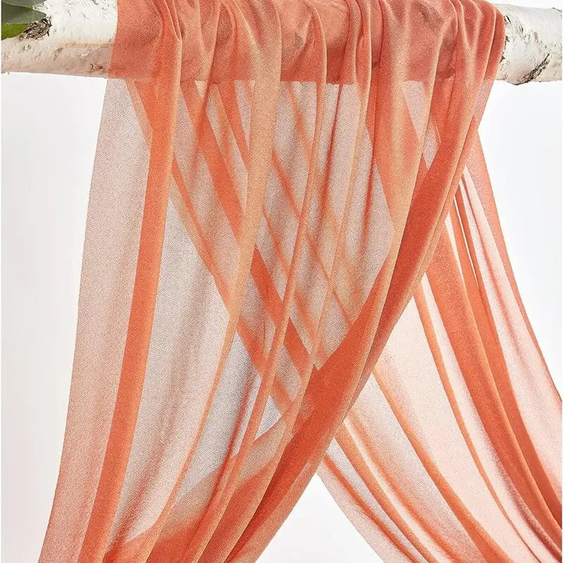 Two panels of sheer orange chiffon fabric draped and gathered for a wedding arch backdrop