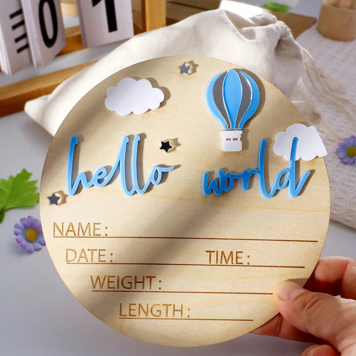 A wooden birth announcement sign featuring blue clouds, a hot air balloon, and lines for name, date, time, weight, and length