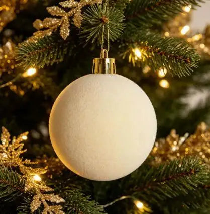 A white velvet flocked Christmas ornament hanging on a green pine branch with gold tinsel.