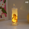 A tall glass candle holder with a glowing yellow flame inside, featuring a depiction of the Virgin Mary.