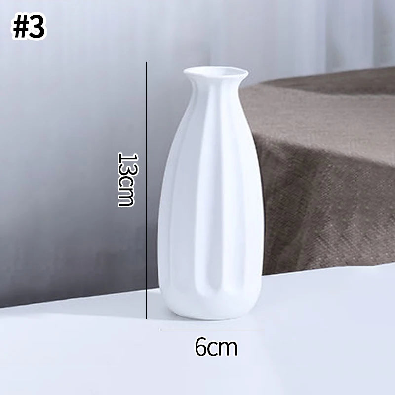A white ceramic bud vase with an elongated, curved shape is shown on a white surface.
