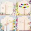 A set of light pink and yellow arch stand backdrops decorated with balloons and banners for birthday or wedding events