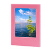 A pink magnetic double-sided frame displaying a scenic view of water and a green tree under a blue sky.
