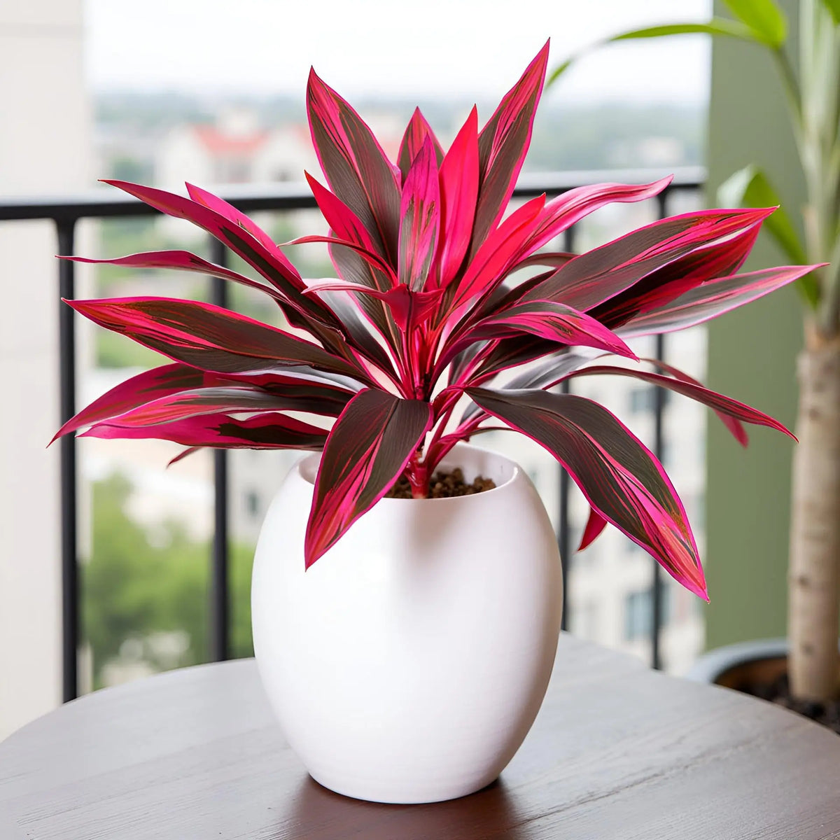 Una vibrante planta tropical artificial magenta brillante en una maceta de cerámica blanca sobre una mesa con una vista borro