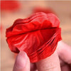 Une main tient un bouquet de pétales de roses artificielles rouges pour la décoration.