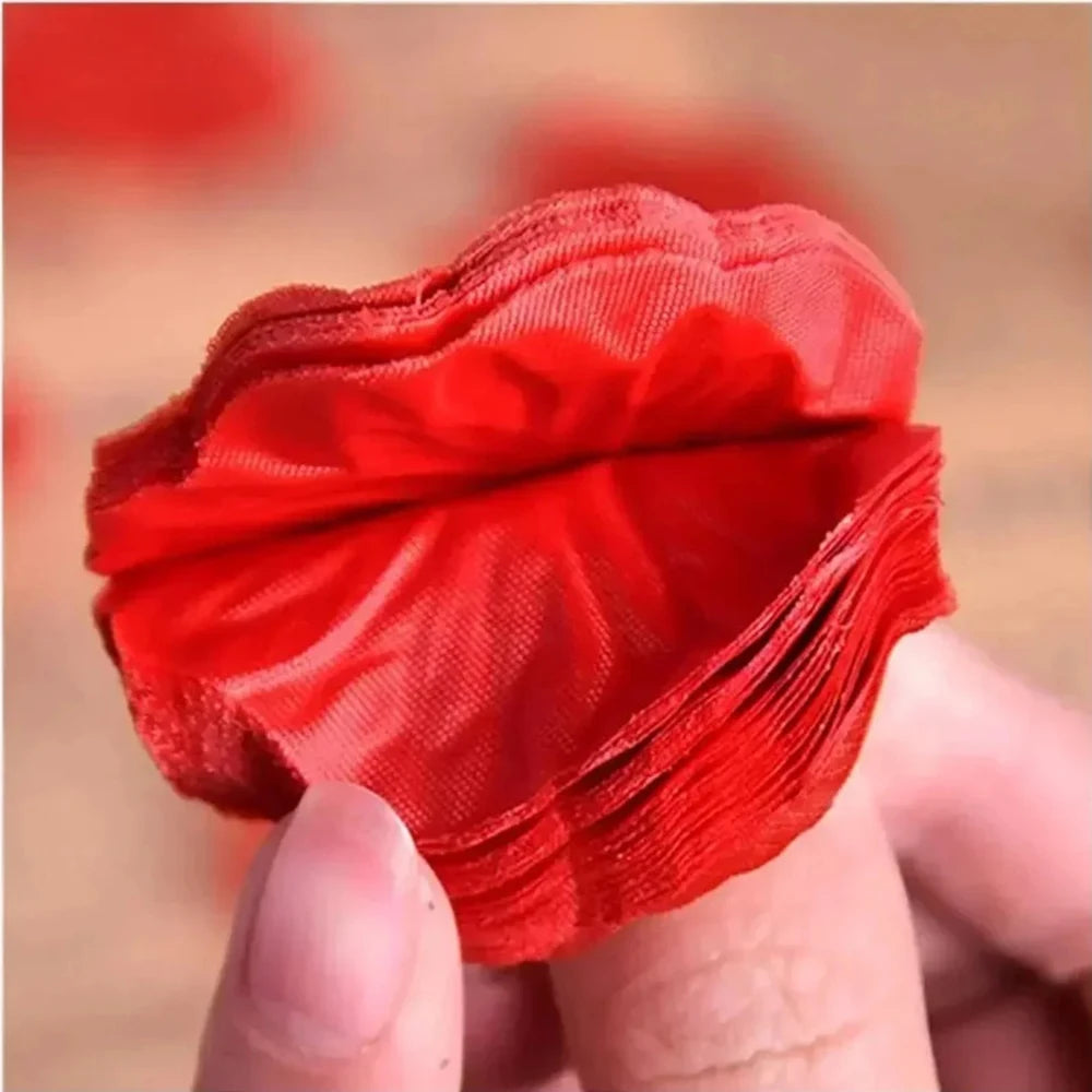 Une main tient un bouquet de pétales de roses artificielles rouges pour la décoration.