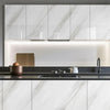 Modern kitchen cabinet featuring white marble-patterned doors and a dark countertop.
