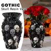Un vase en résine noire rempli de crânes décoratifs et de roses rouges.