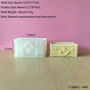 A white silicone mold shaped like a rectangular handbag is shown next to a finished yellow candle product.