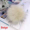 Pompon en fausse fourrure beige, accessoire pour les cheveux, exposé sur un livre.